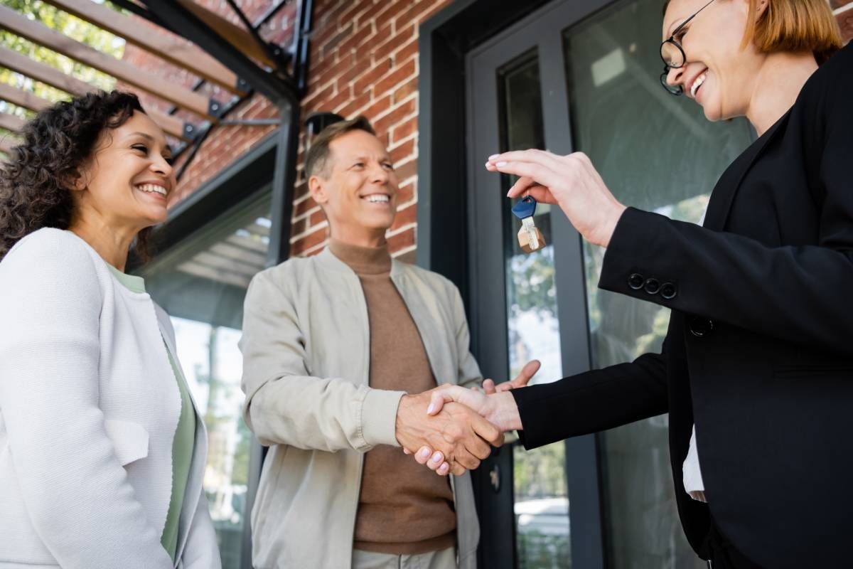 A realtor giving the keys to the owners of a new home in Indiana at Kentuckiana Real Estate Academy near Lexington, KY