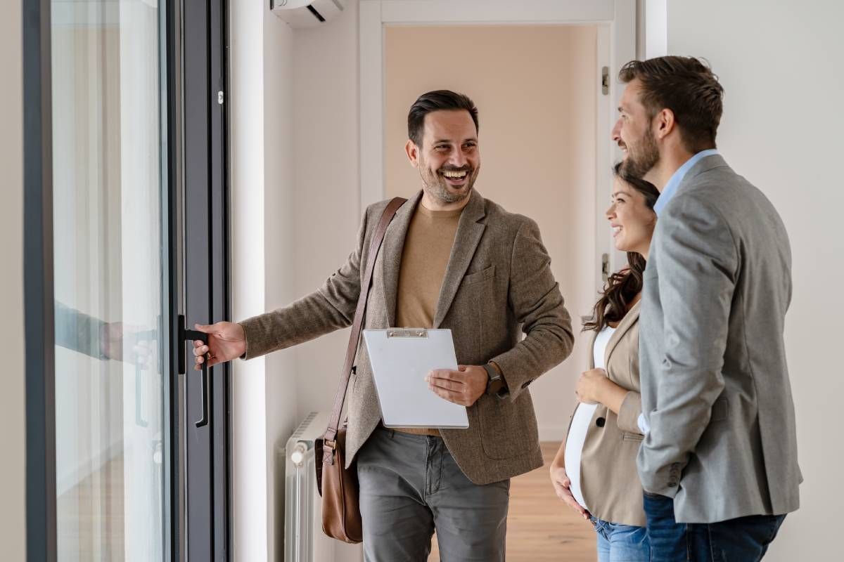 A real estate agent showing a property to a young married couple at Kentuckiana Real Estate Academy near Lexington, KY