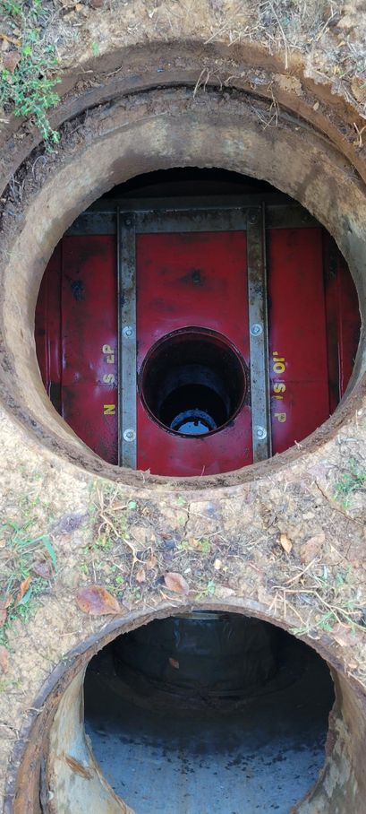Red circular tunnel openings in a weathered wall, with a smaller pipe visible inside the upper opening.