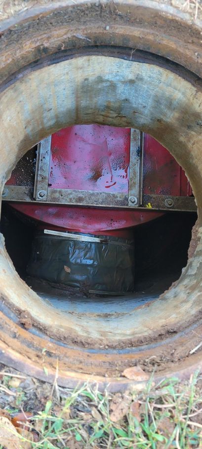 Close-up of a large rusted pipe opening with a red valve or machinery visible inside.