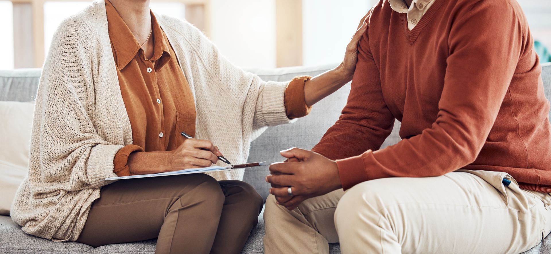 A man and a woman are sitting on a couch talking to each other.