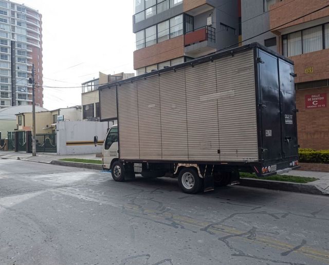 Camión de reparto estacionado en una calle de la ciudad junto a edificios de apartamentos.