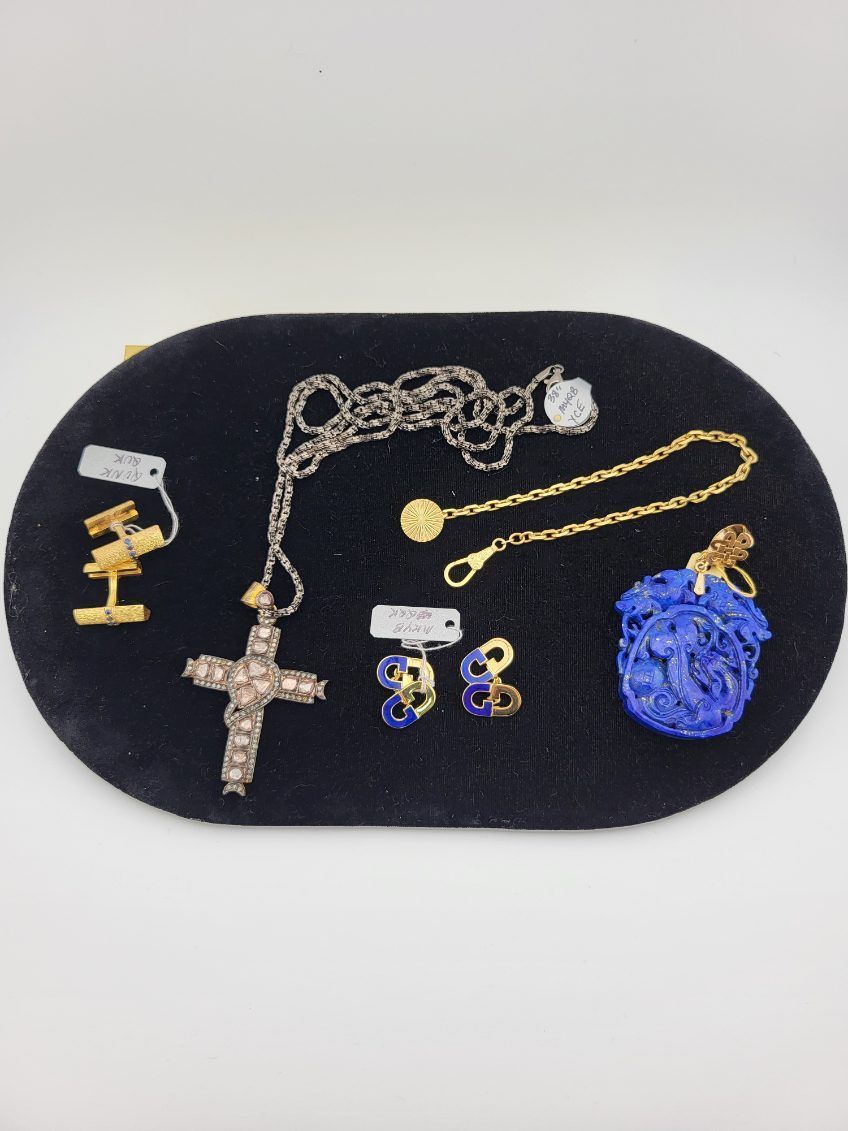 Jewelry display on black oval. Includes a cross pendant, earrings, a bracelet, and a blue orb.