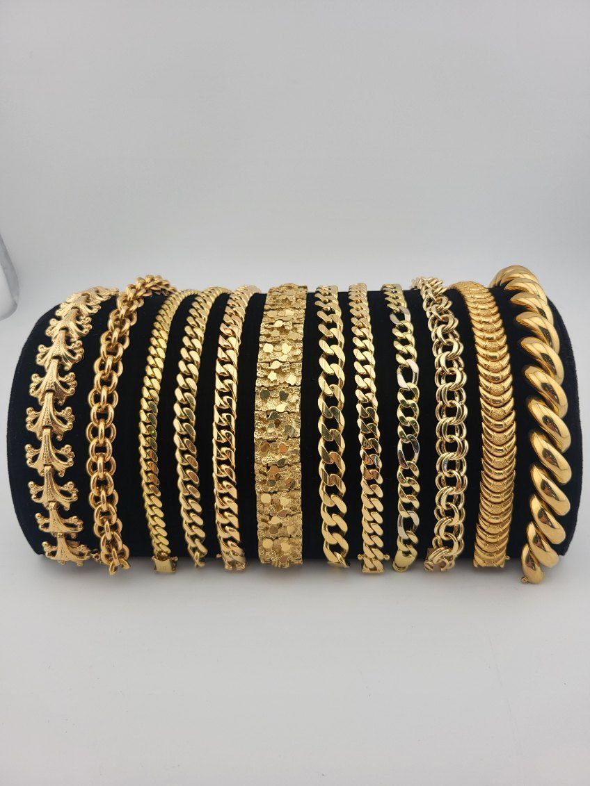 Gold chain bracelets and black-and-gold bangles arranged in rows on a black display roll