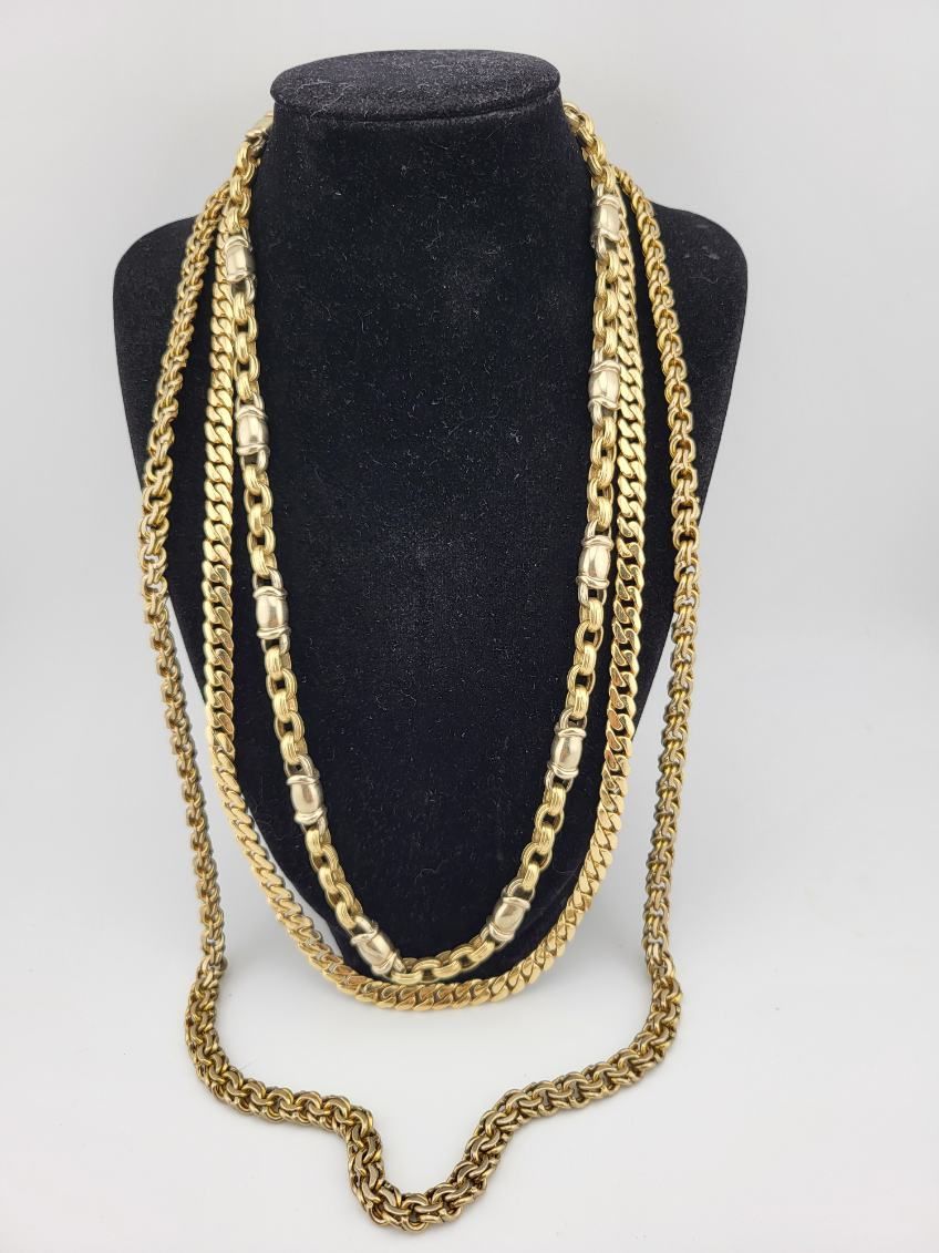 Gold chain necklaces draped over a black display bust on a white background