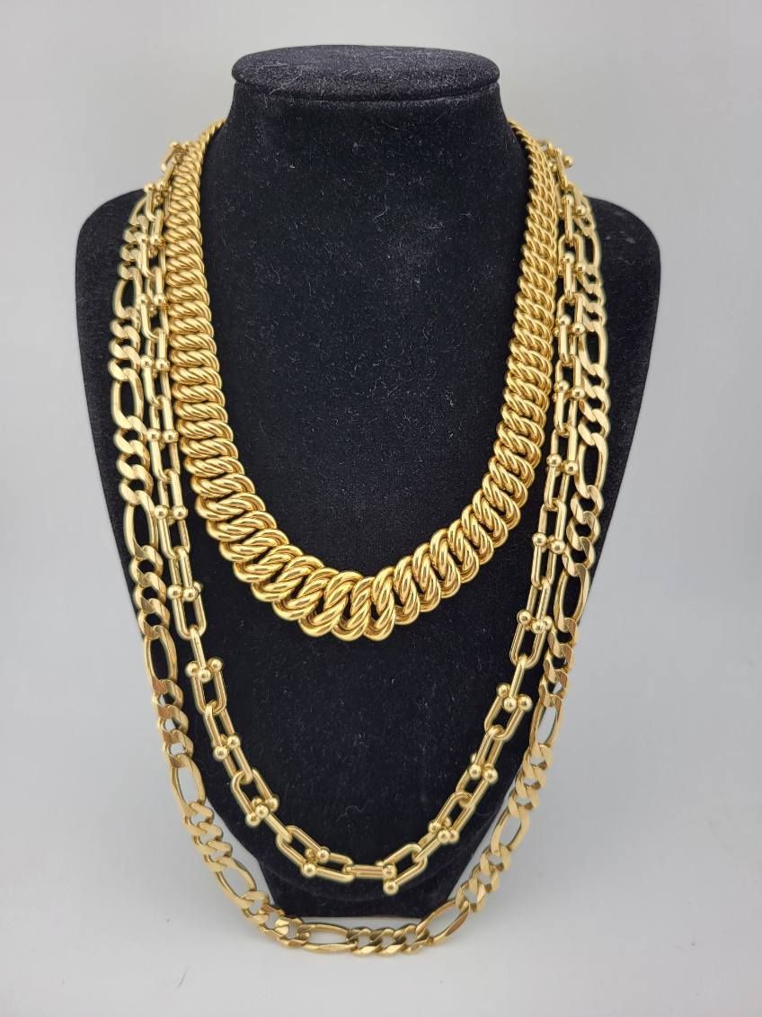 Three gold chain necklaces displayed on a black bust form display.