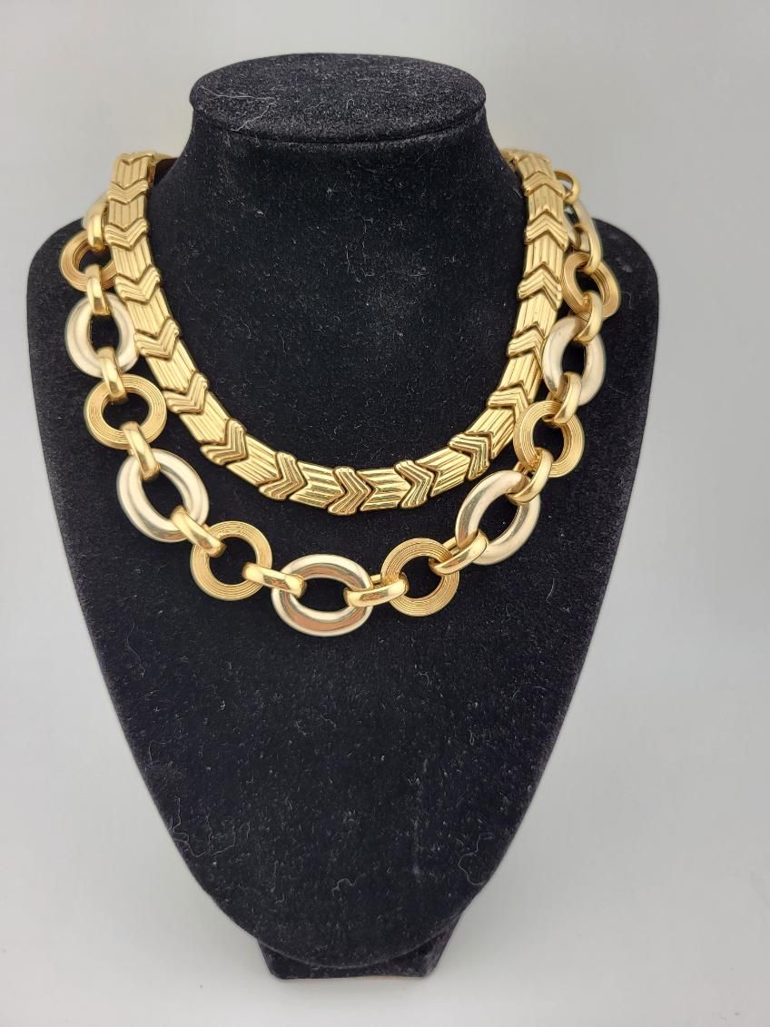 Black velvet necklace bust displaying layered gold chain necklaces on a plain background