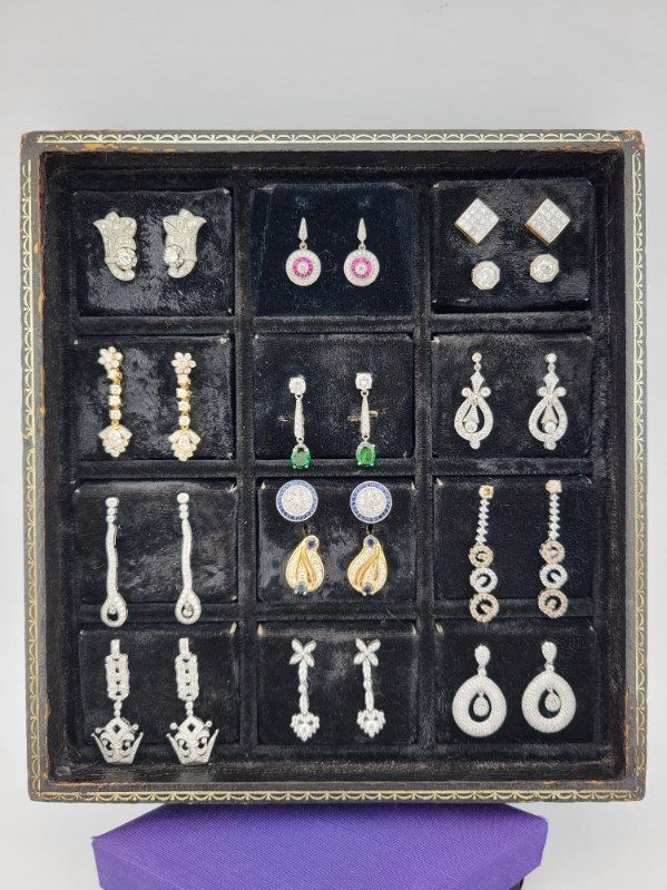 Tray of various diamond and gemstone earrings displayed on a black velvet surface.