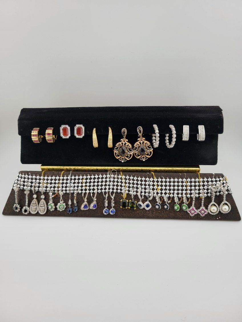 Earrings displayed on black and brown jewelry holders. Various styles and colors are visible.
