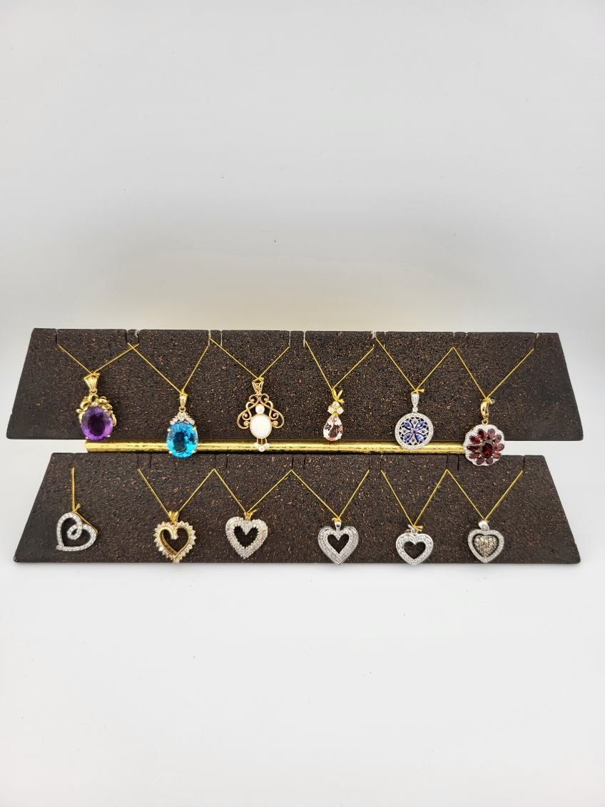 Two-tier dark display stand with assorted dangling gold and gem heart, teardrop, and round necklaces