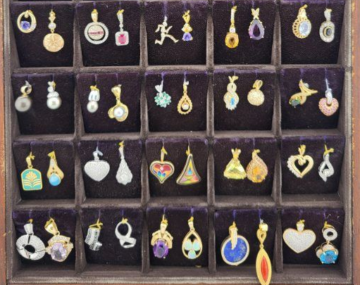Tray of assorted colorful dangling earrings arranged in small black compartments.