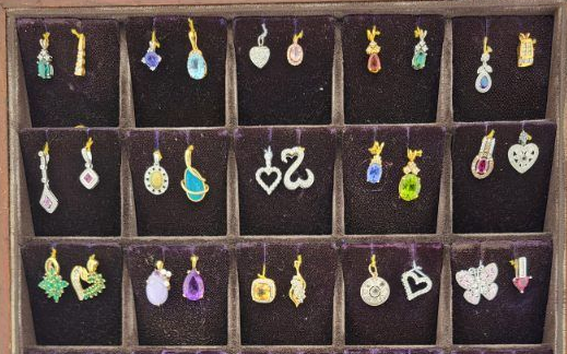 Display of colorful dangling earrings arranged in rows on a dark background