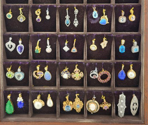 Jewelry display of assorted colorful pendant necklaces arranged in a wooden compartment shelf