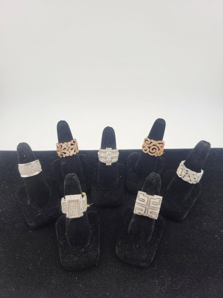 Black velvet display with several silver and gold rings on black ring stands.