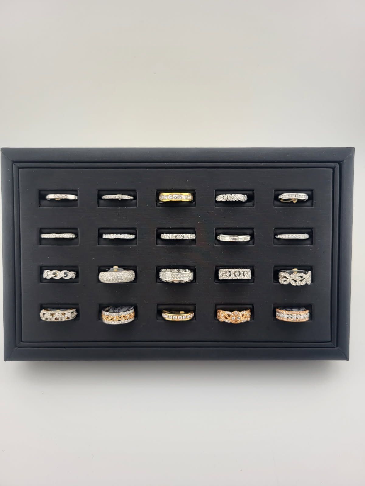 Framed display of 15 rings arranged in rows on a dark background