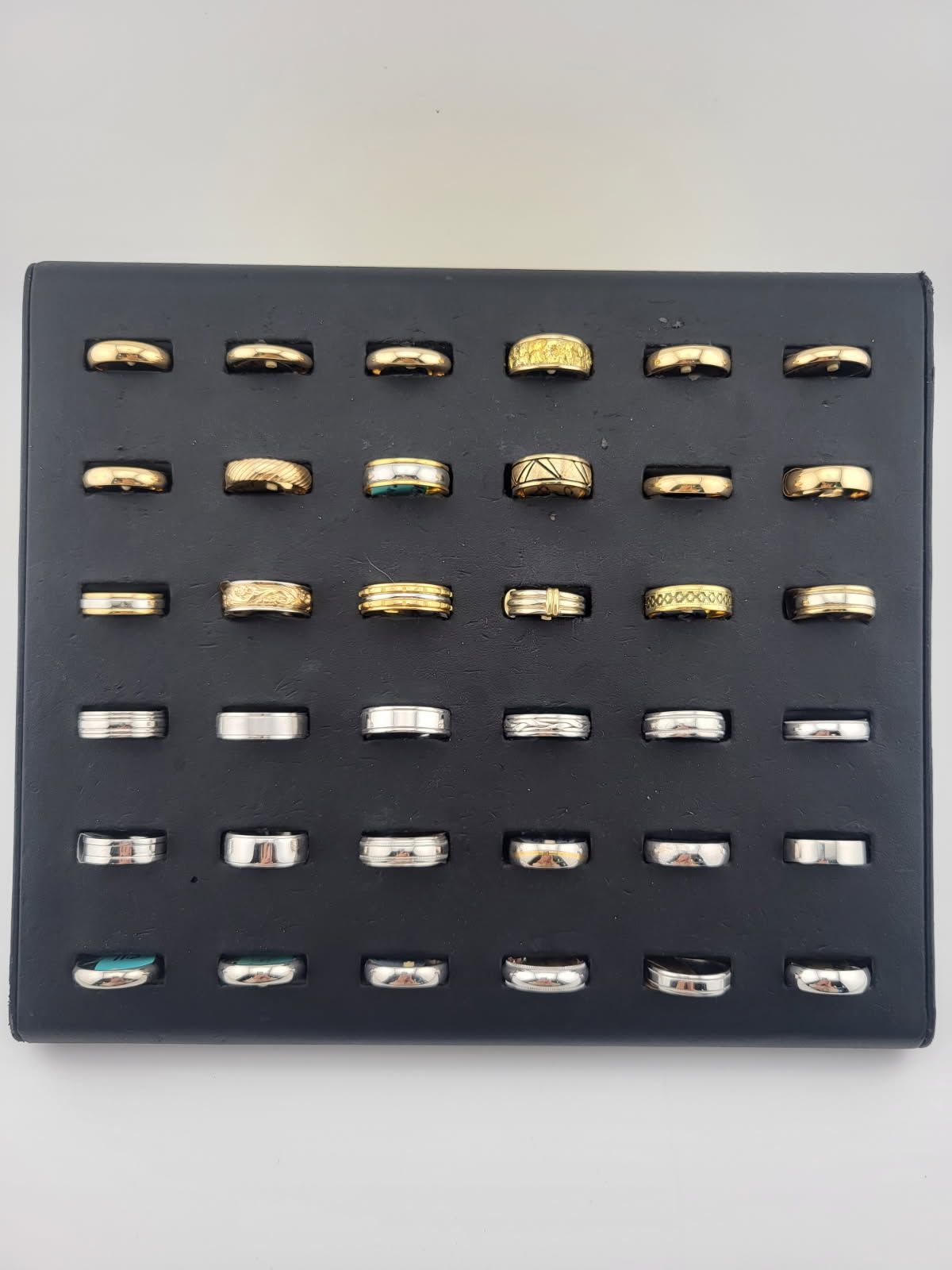 Black display board with rows of assorted metal watch bands or clasps arranged neatly.