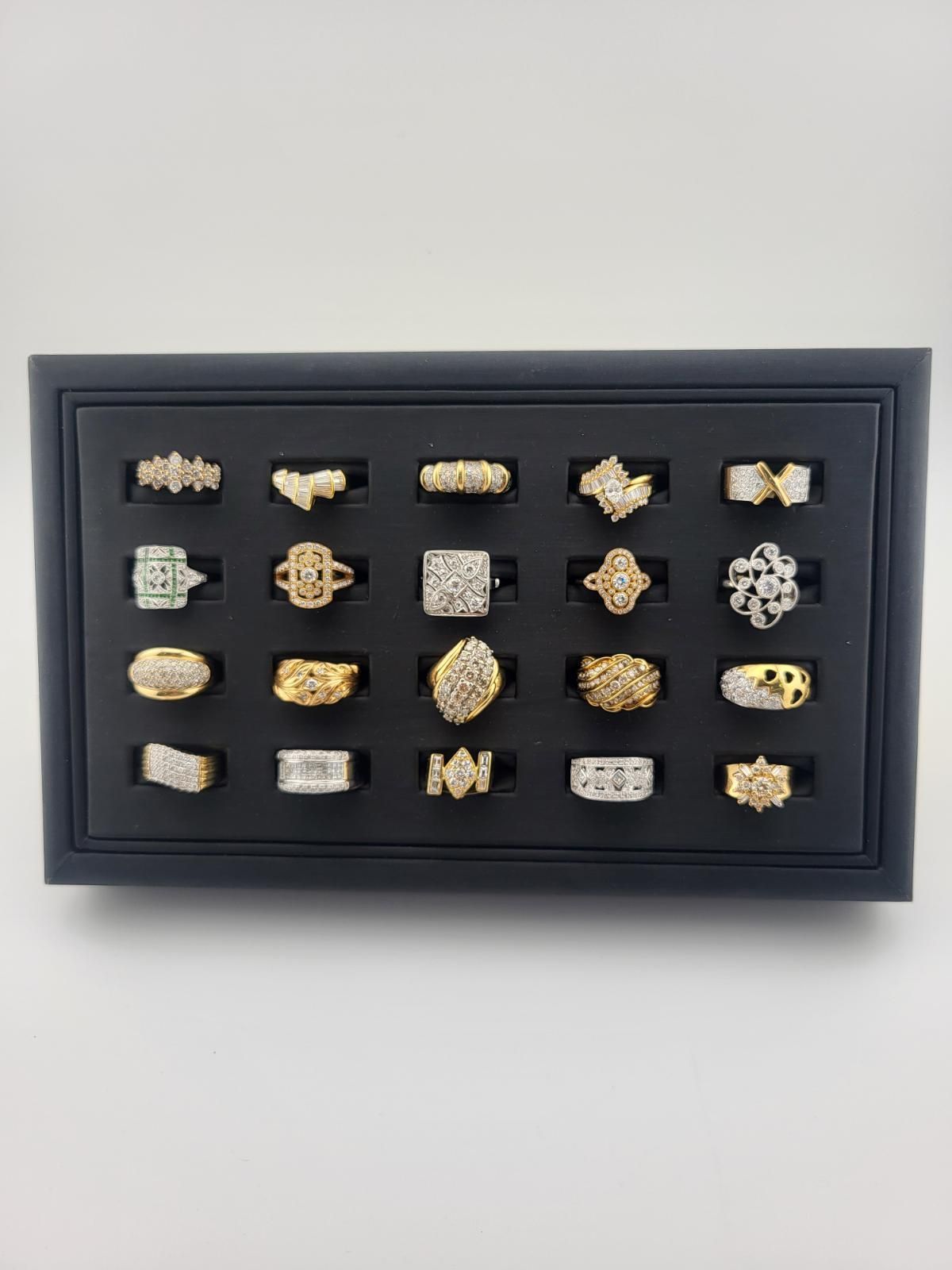 Framed display of 20 gold and silver ring-like specimens arranged in a grid on black backing