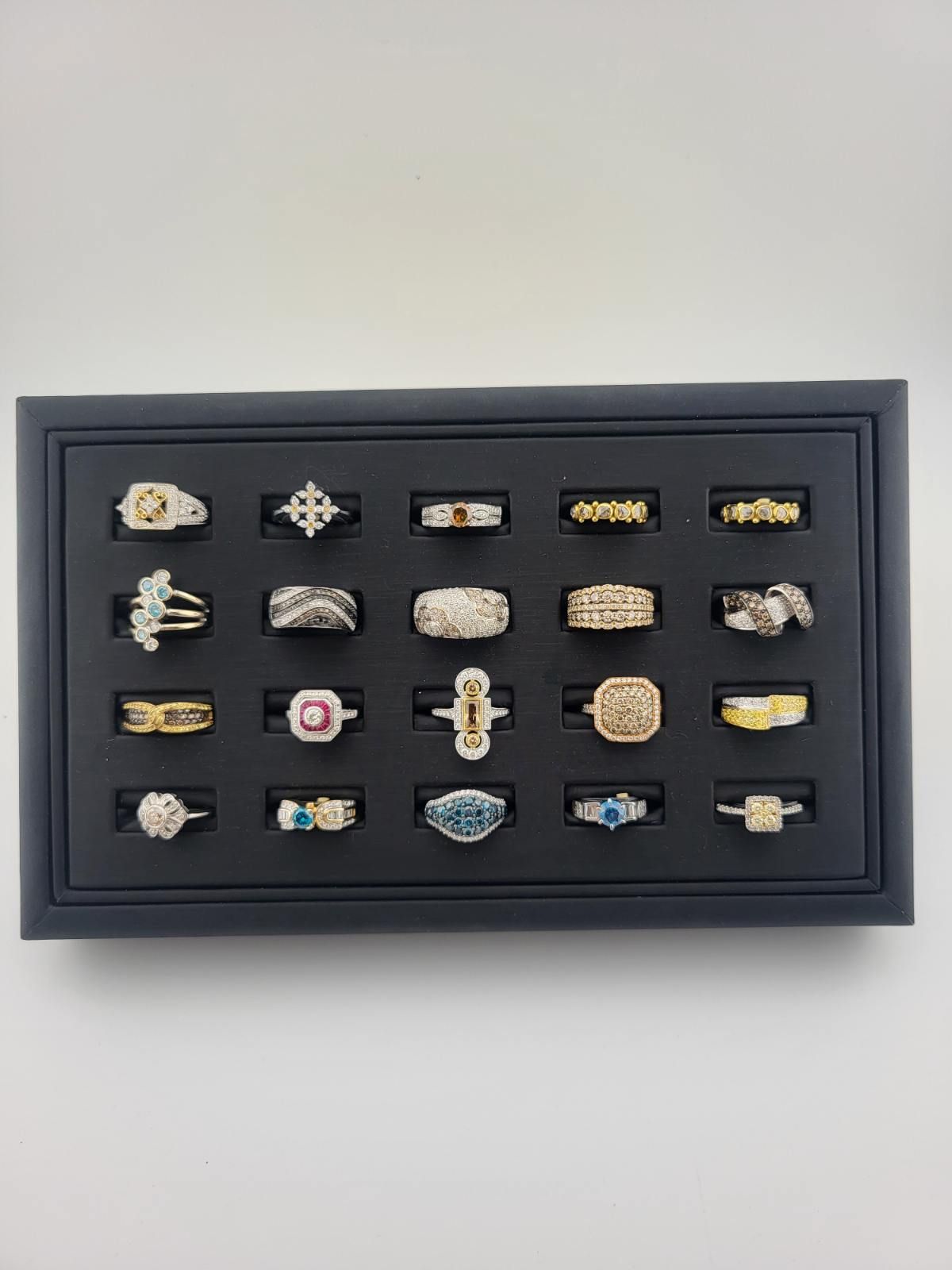 Framed display of assorted decorative rings and pins arranged in rows on a black background