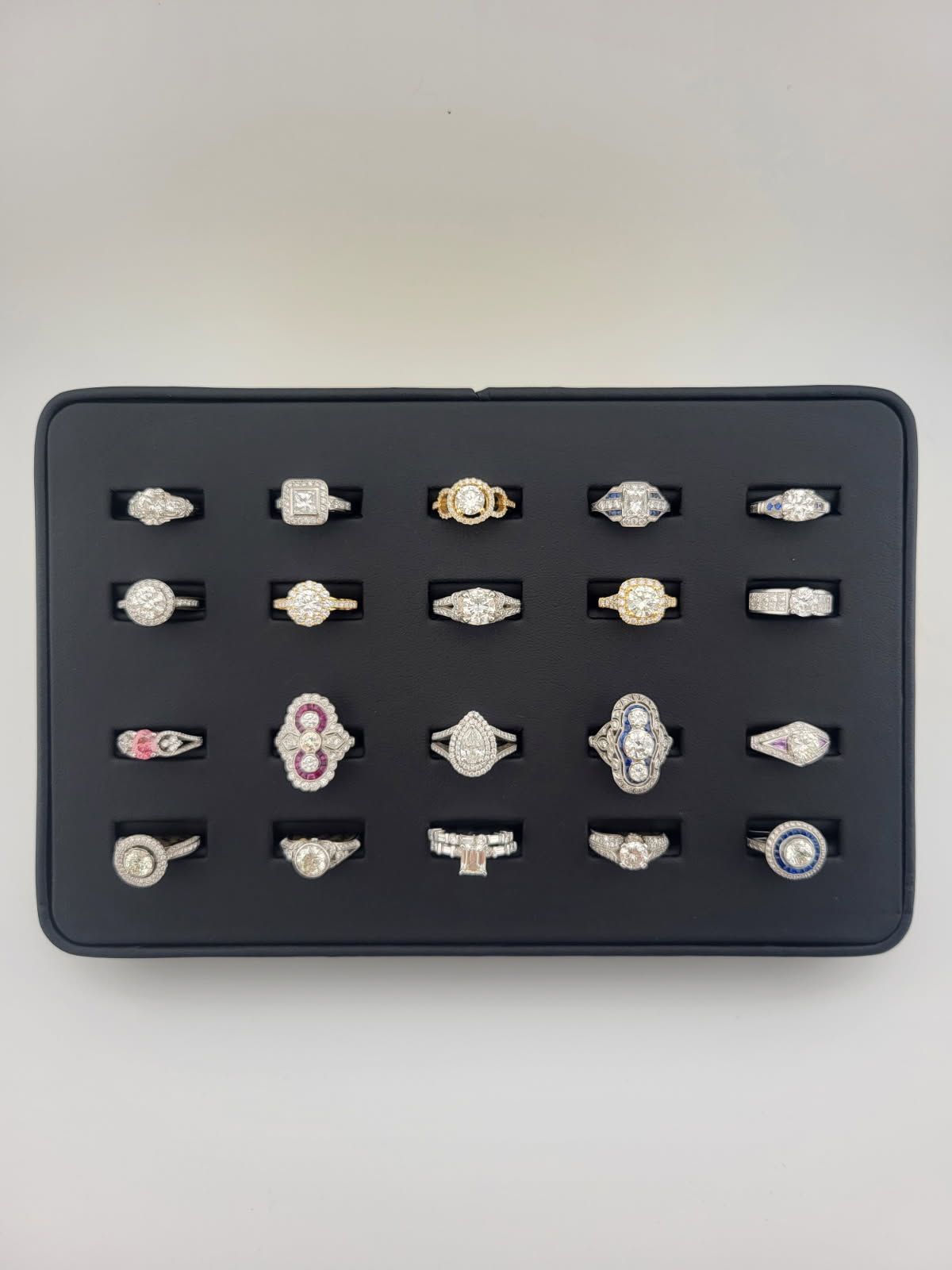 Assorted rings arranged in a black presentation box on a light background