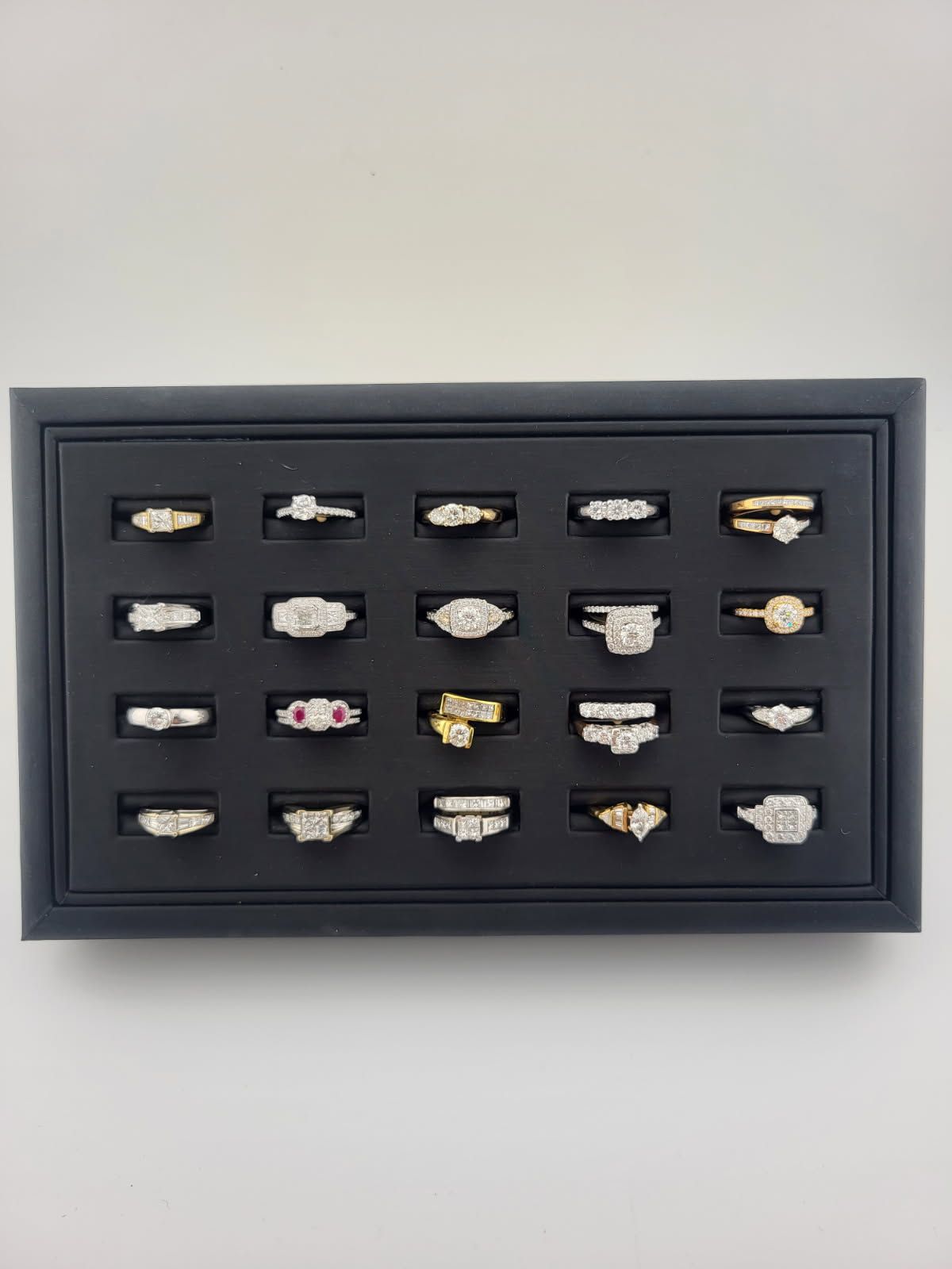 Shadow box display of 20 small lip-shaped pins in a black frame on a white wall