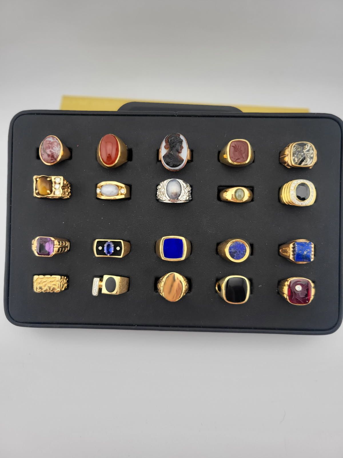 Display case with multiple colorful rings arranged in rows on a black tray
