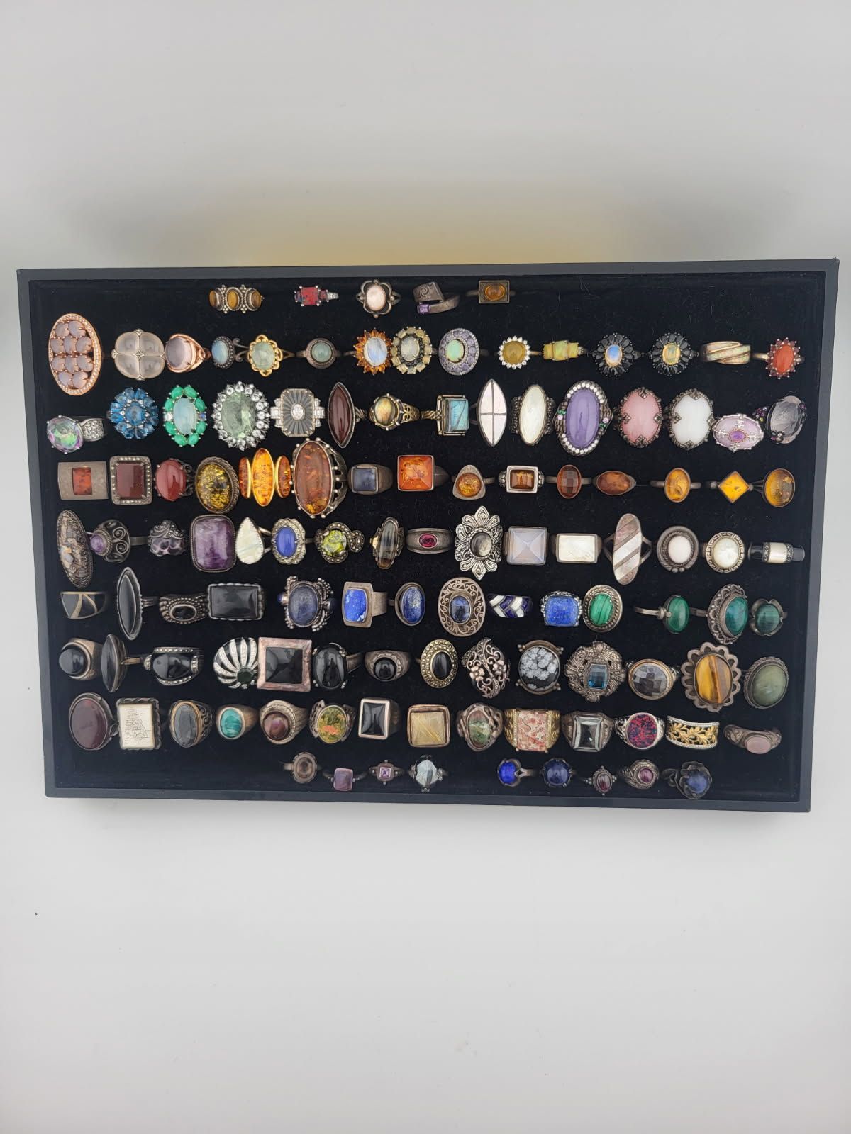 Framed display of many colorful wristwatches arranged in rows on a wall