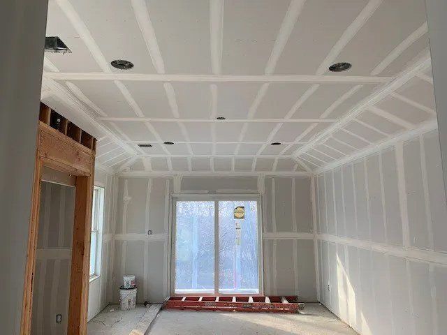A room with drywall walls and a ladder in it.
