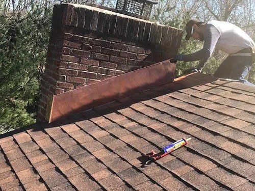 A man is working on a roof next to a chimney.