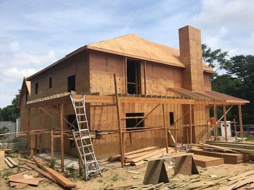 A house is being built out of plywood with a ladder in front of it.
