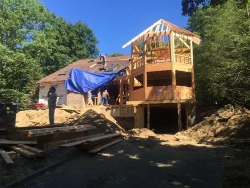 A house under construction with a blue tarp on the roof