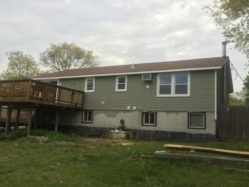 The back of a house with a deck and a lot of windows.