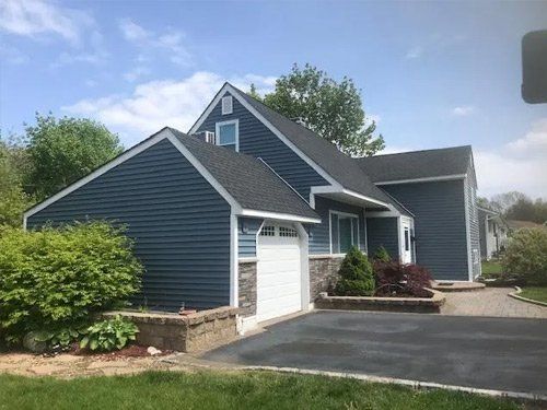 A blue house with a white garage door and a black roof.