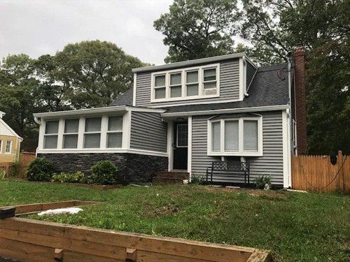A house with a lot of windows and a wooden fence in front of it.