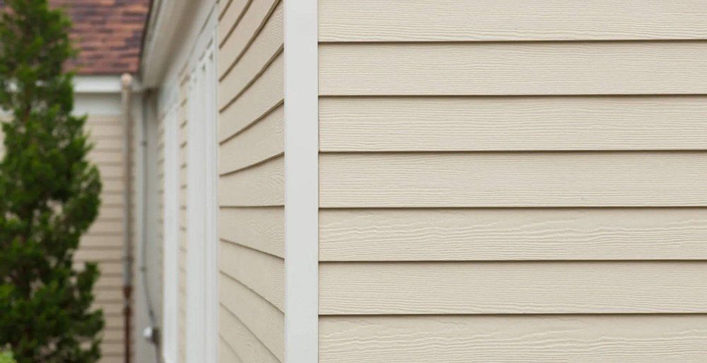 A close up of a house with siding and a tree in the background.