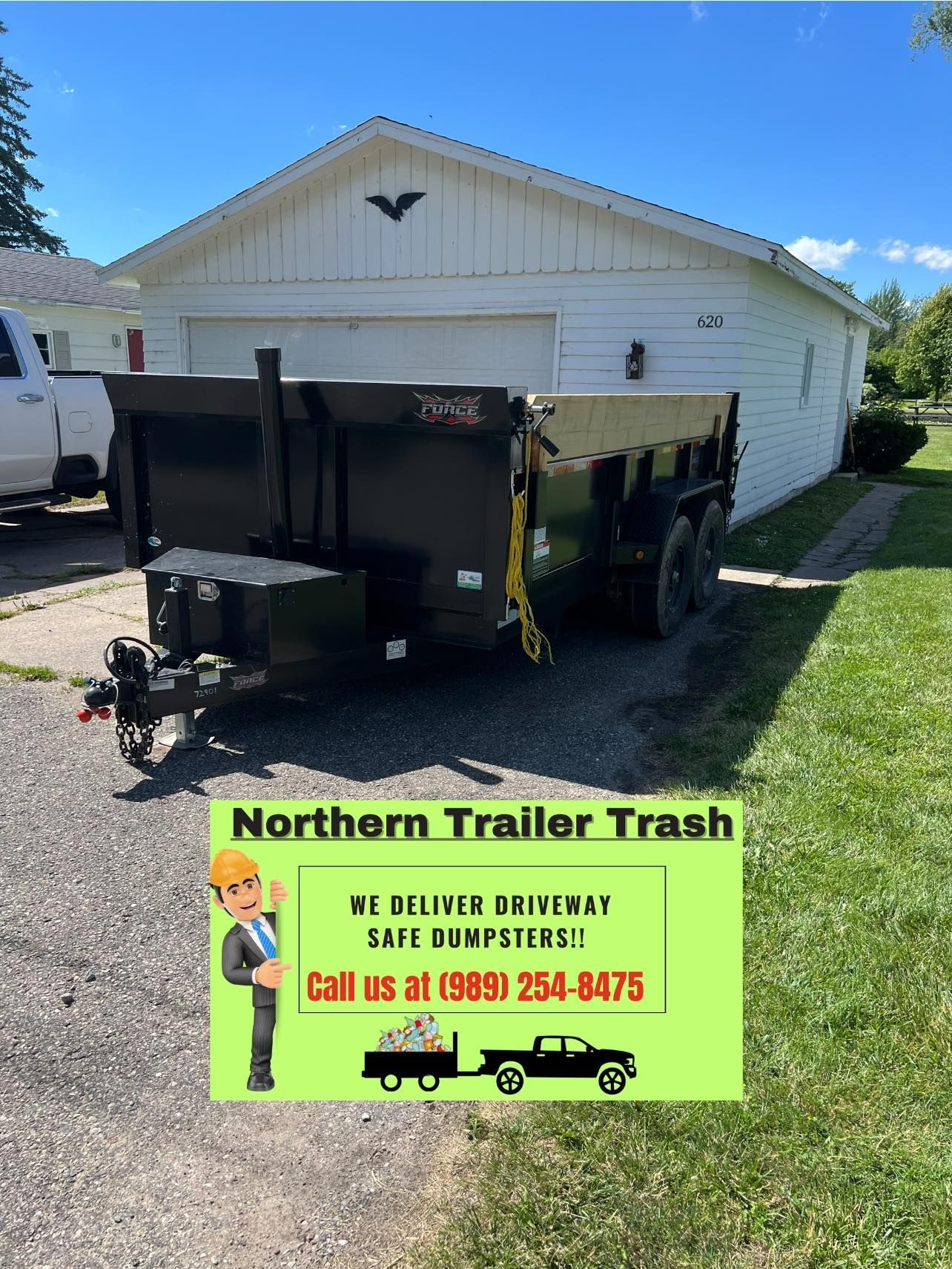 A black trailer in front of a white house. Advertisement for 