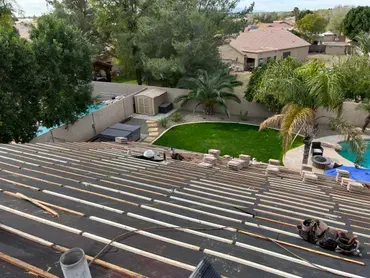An aerial view of a roof under construction with a pool in the background.