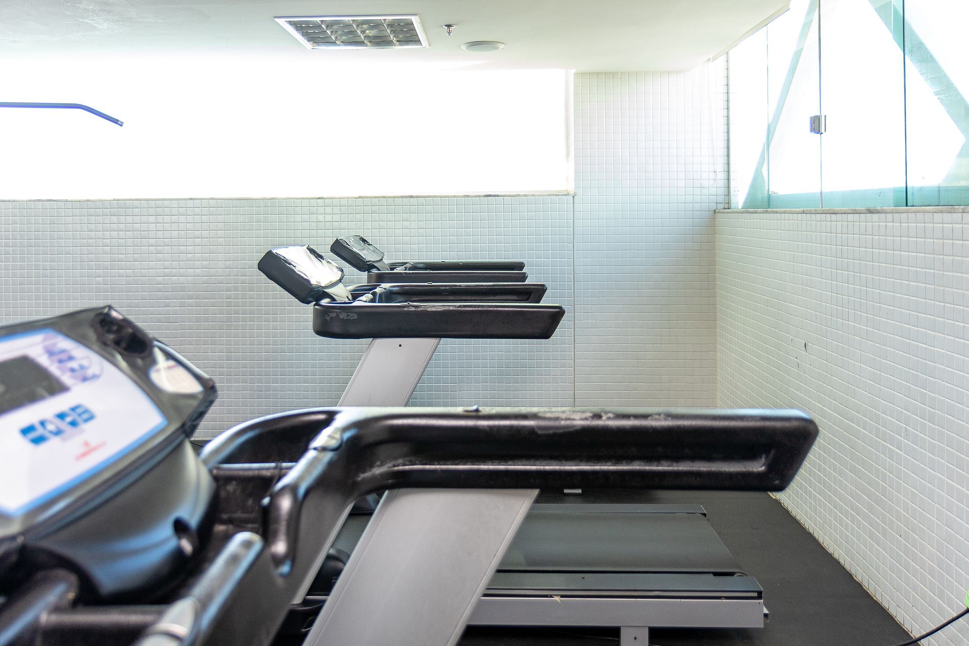 Sala de cardio moderna de academia, com esteiras ao longo de uma parede bem iluminada