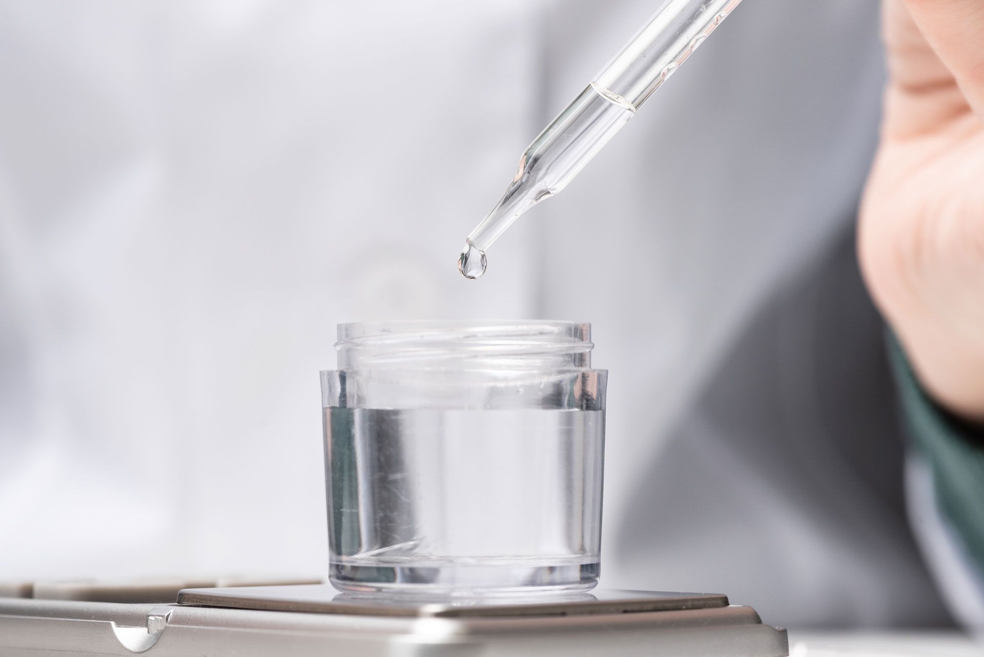 Dropper dispensing liquid into a clear glass vial on a lab bench