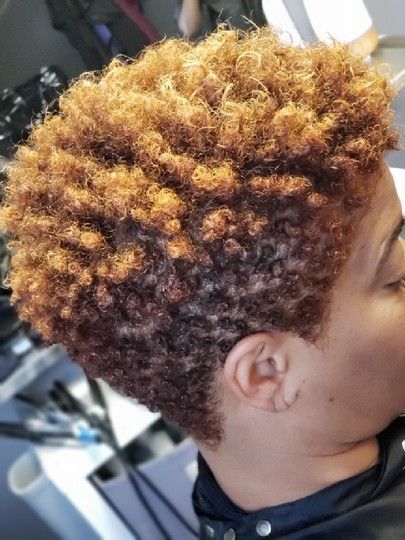 Woman with short, curly, auburn hair. Side view, wearing a black jacket.