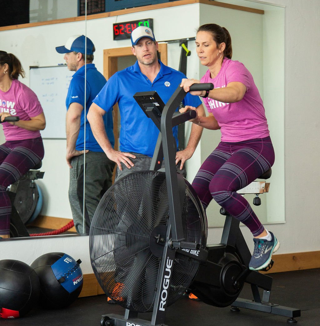 A man and a woman are riding an exercise bike in a gym