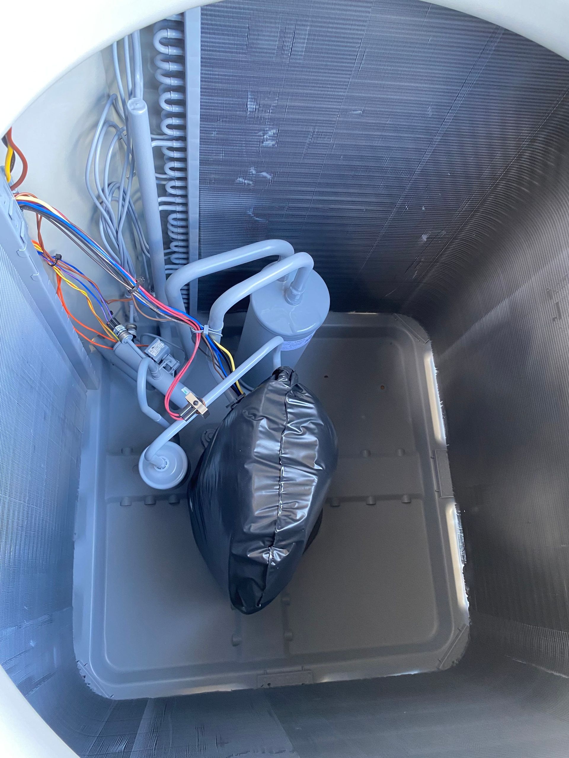 A blue air conditioner condenser coil and internal copper piping mounted on a wooden pallet.