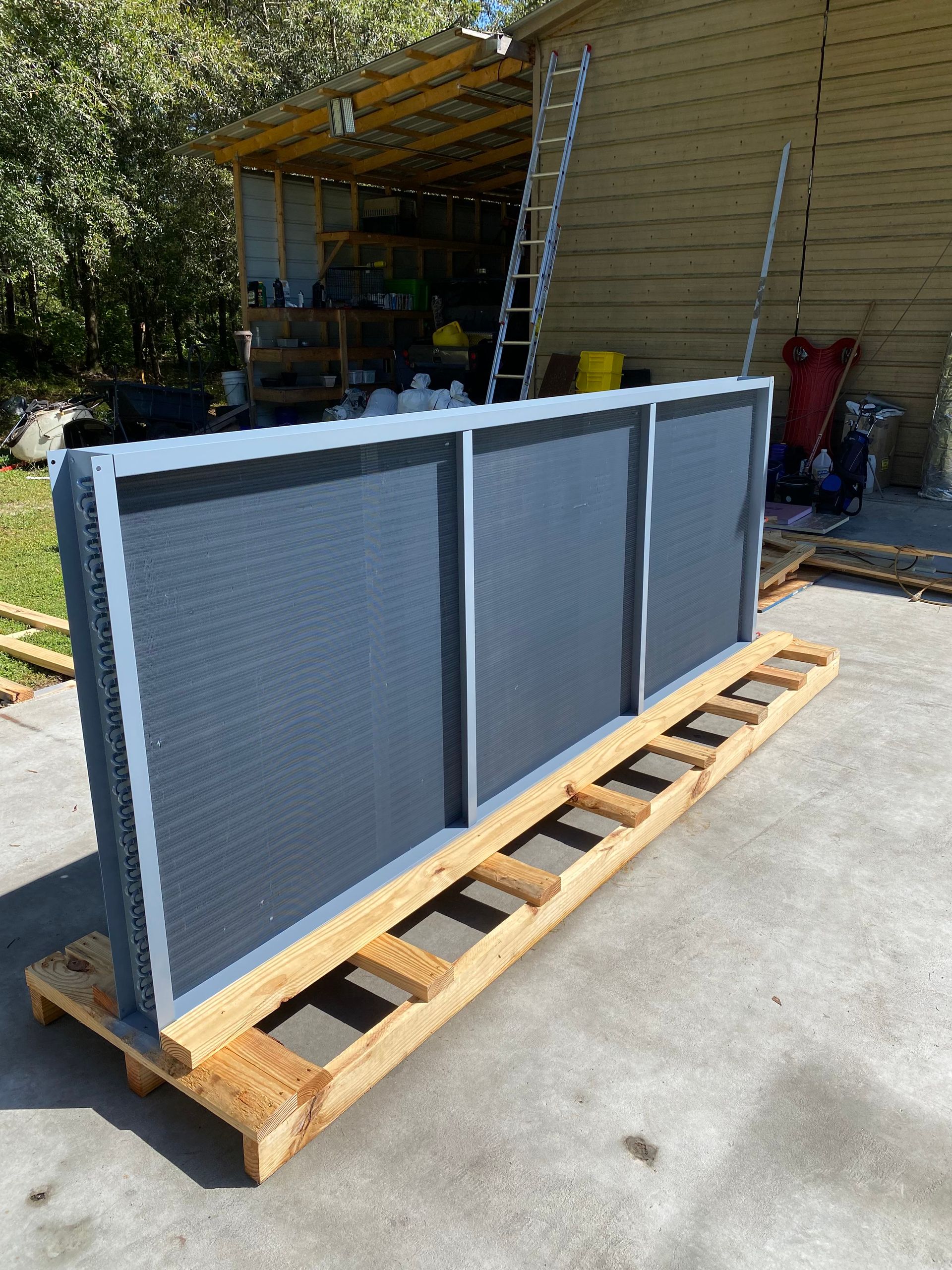 An open HVAC unit cabinet showing two grey vertical compressors connected by pipes and wiring against a metal frame.