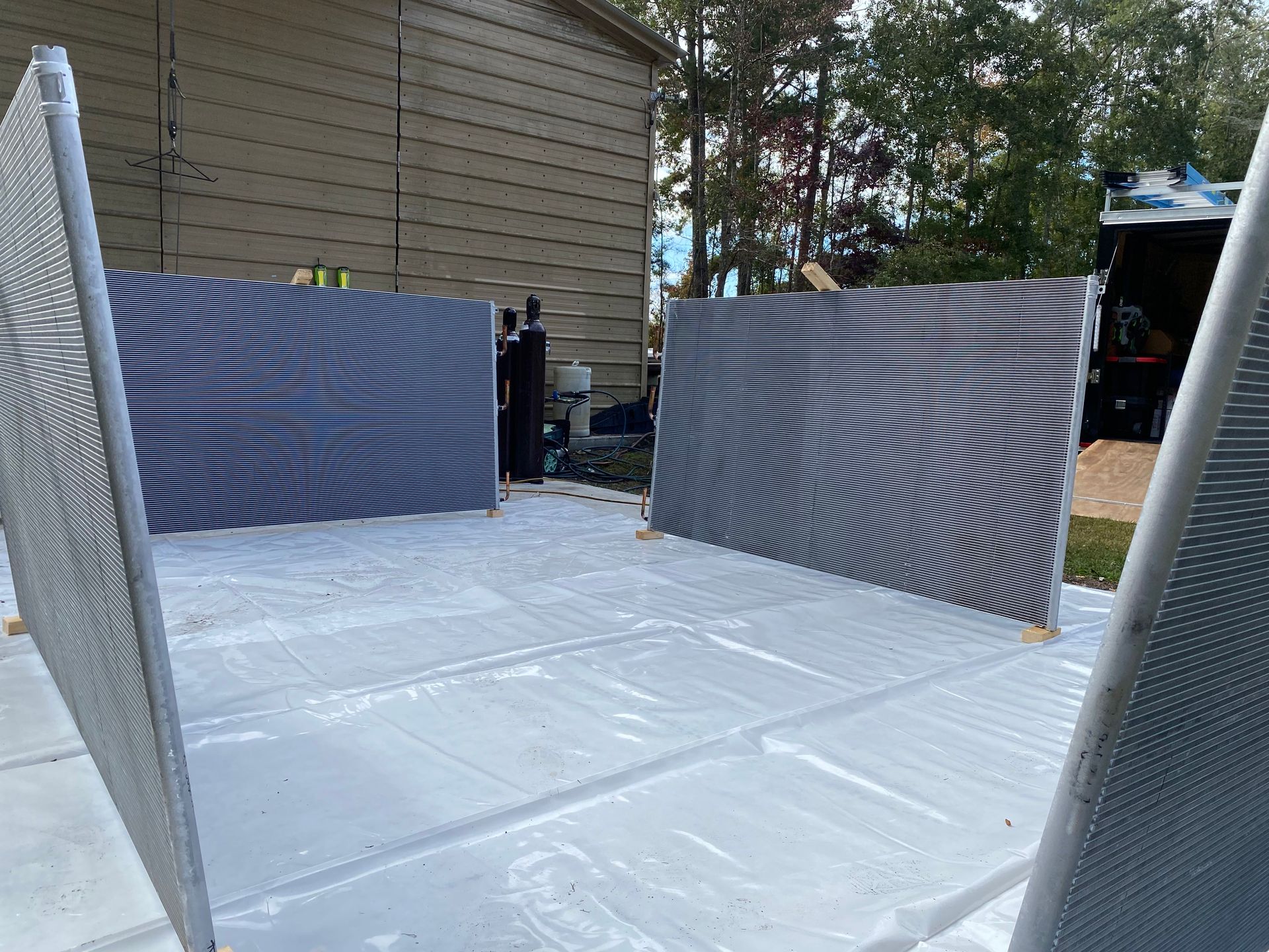 A blue air conditioner condenser coil and internal copper piping mounted on a wooden pallet.