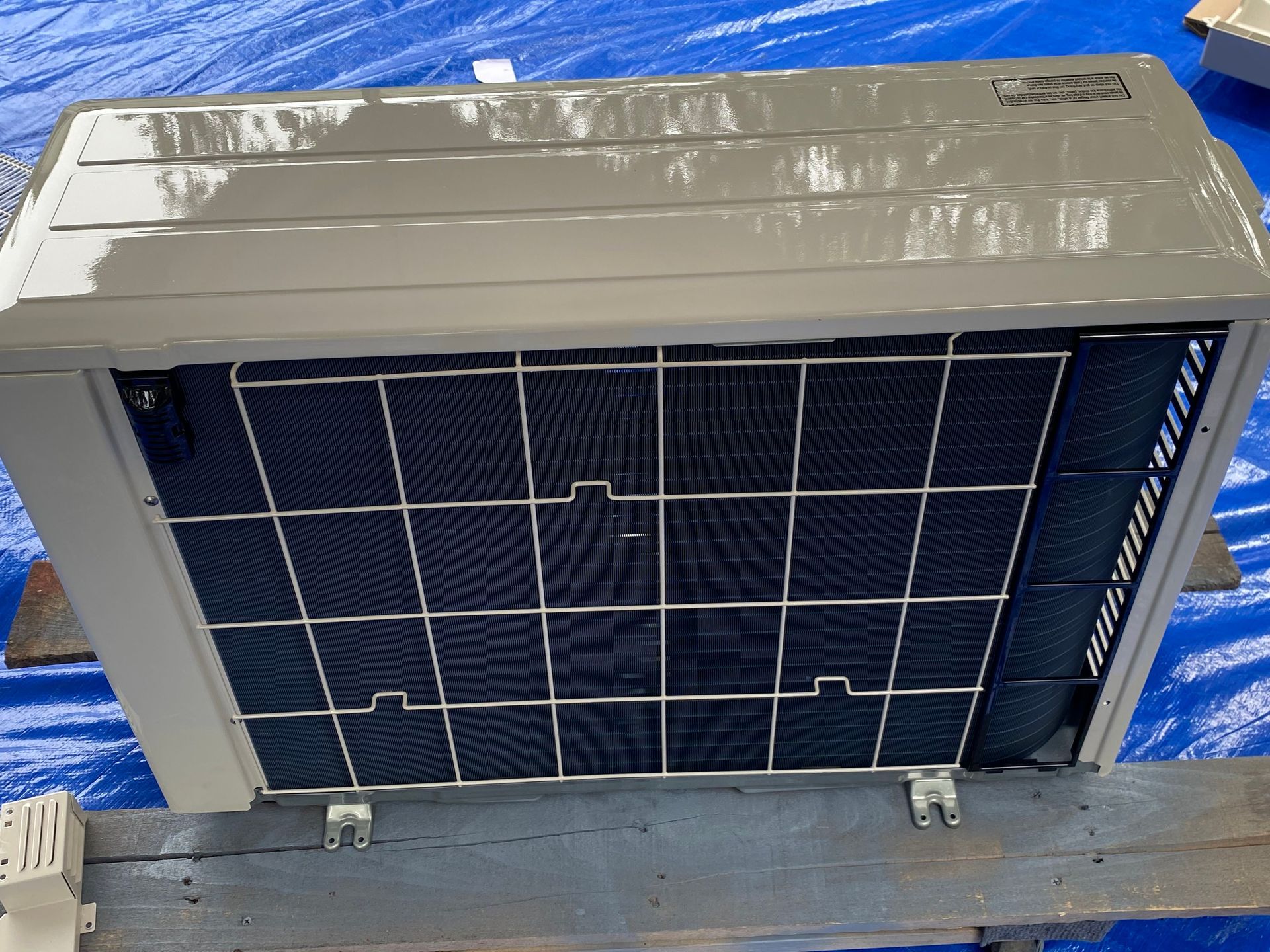 The interior of an HVAC air handler unit featuring an A-frame evaporator coil assembly with metal tubing and drain ports.