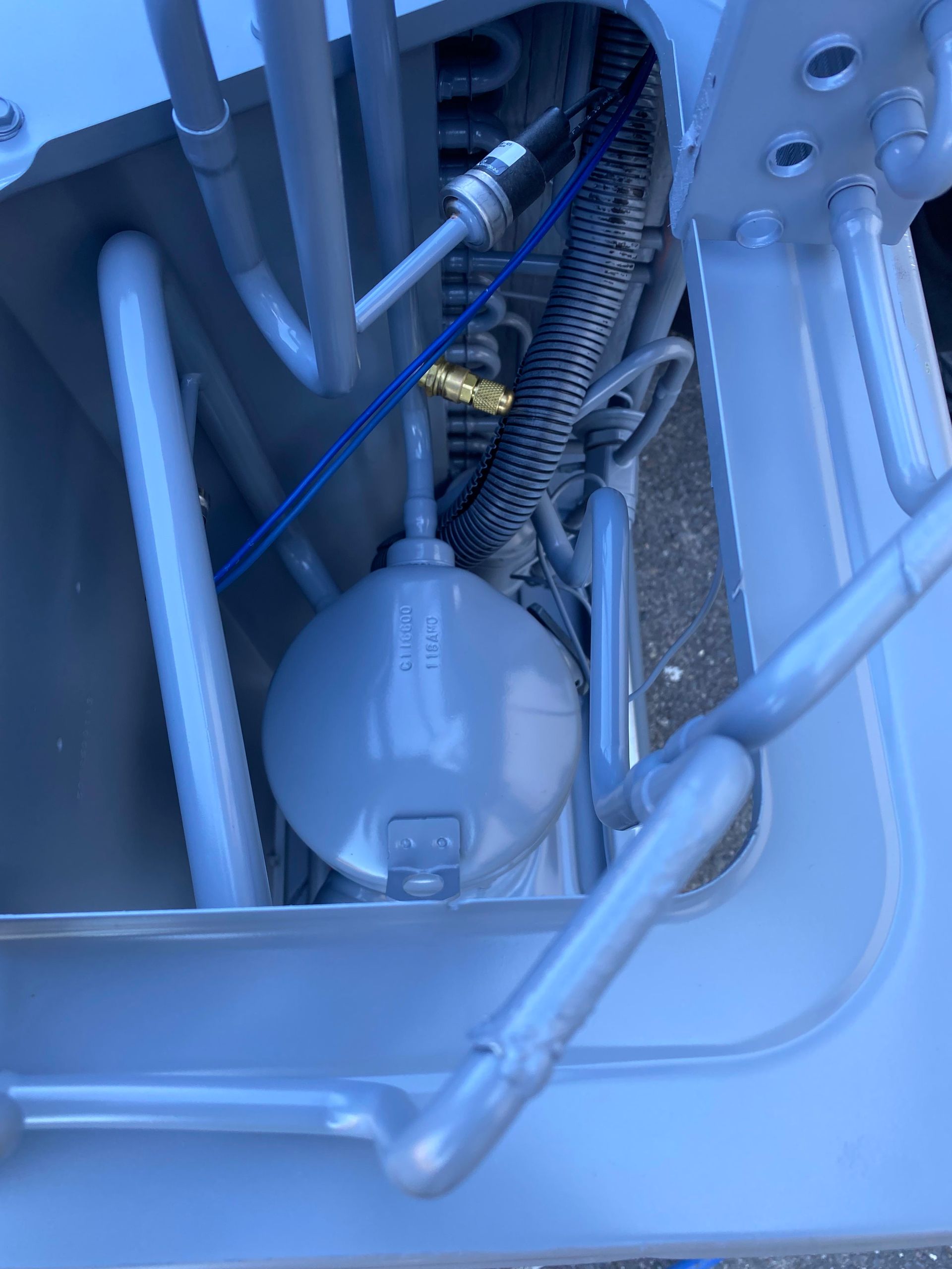The interior of an HVAC air handler unit featuring an A-frame evaporator coil assembly with metal tubing and drain ports.