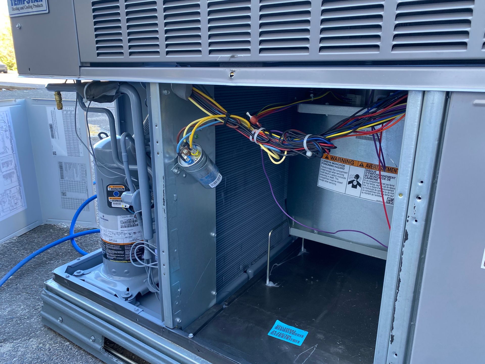 The interior of an HVAC air handler unit featuring an A-frame evaporator coil assembly with metal tubing and drain ports.
