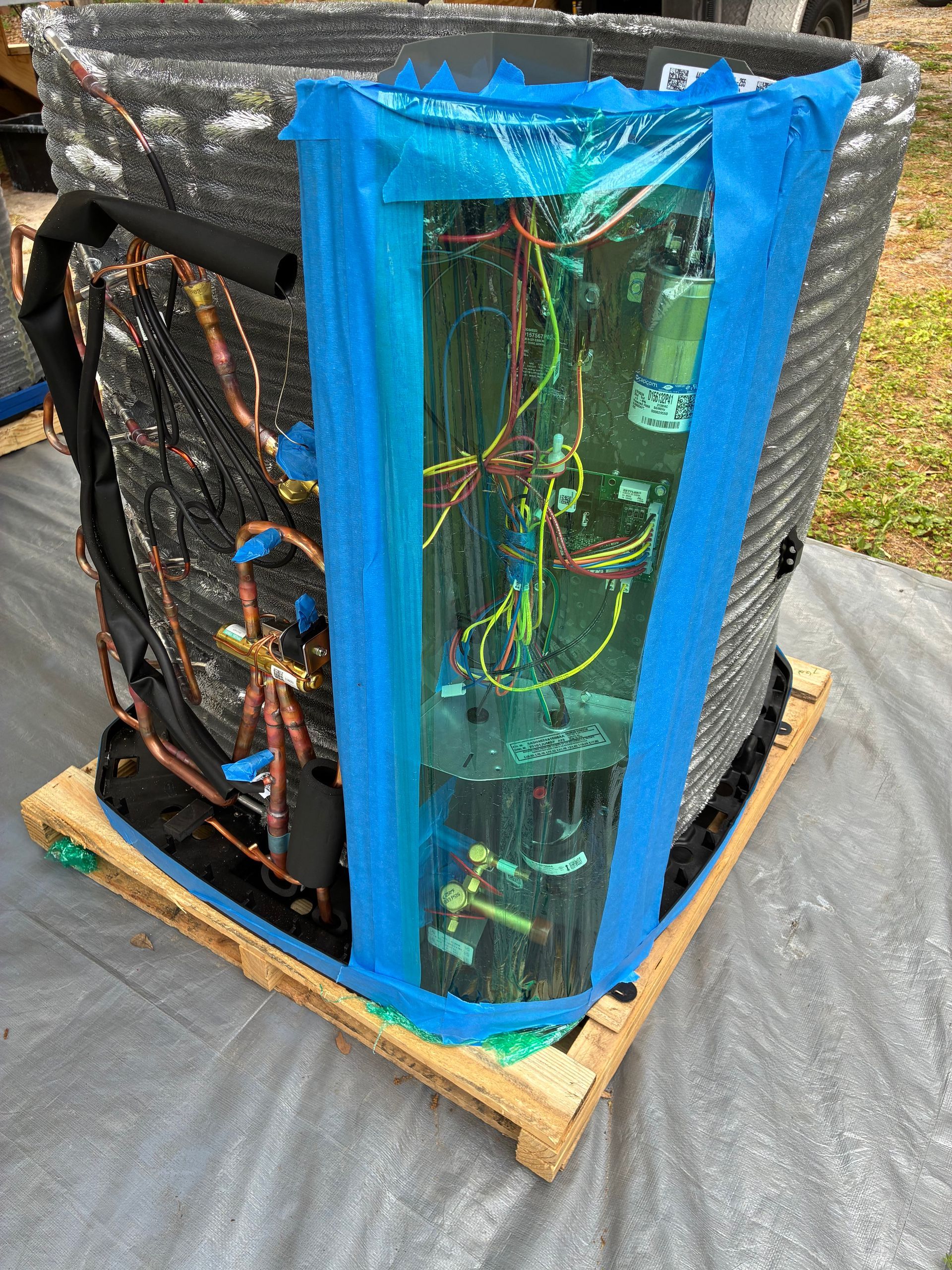 An open HVAC unit cabinet showing two grey vertical compressors connected by pipes and wiring against a metal frame.
