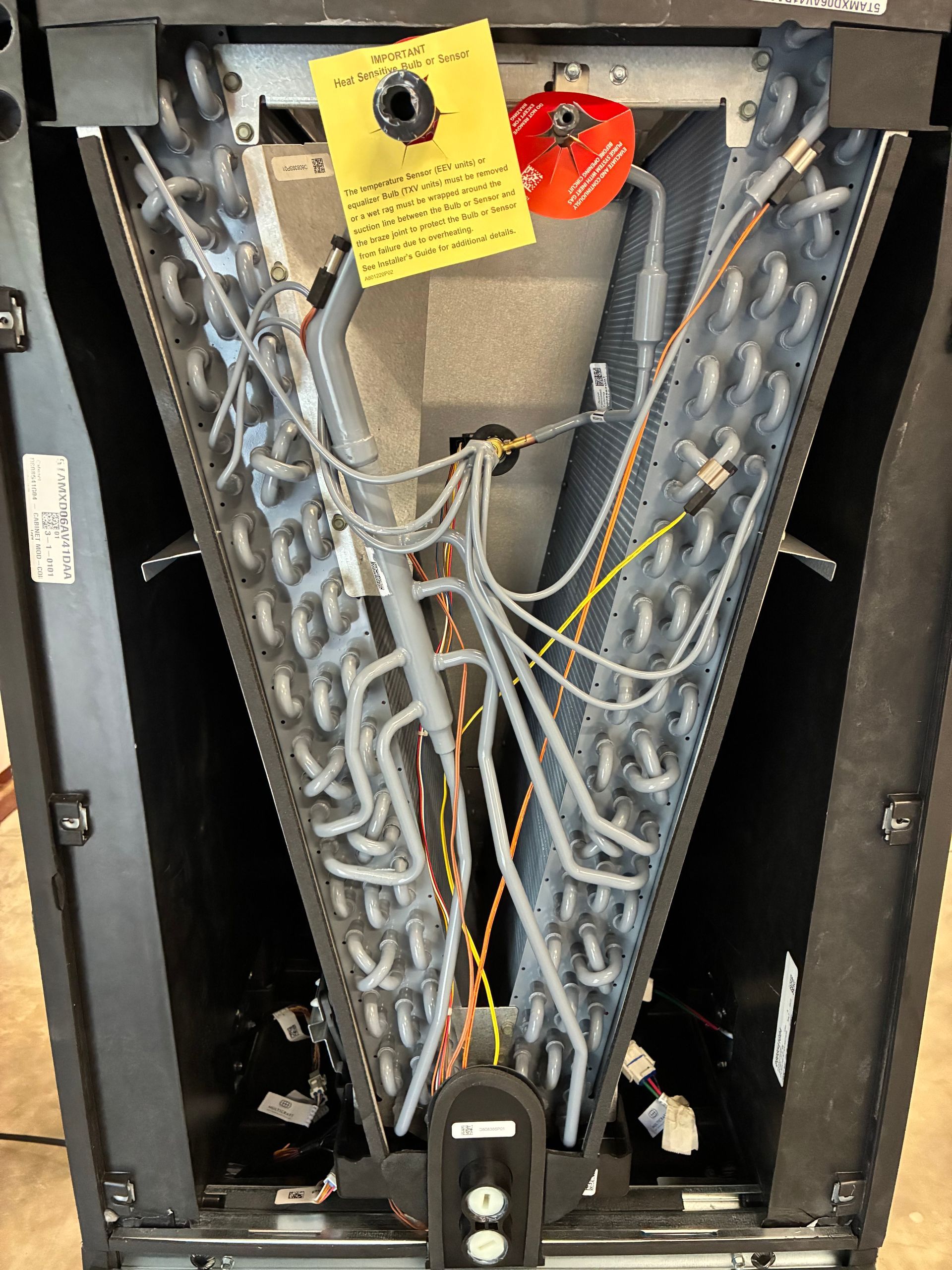 The internal components of an industrial HVAC unit are shown, featuring wiring, circuit boards, and a grey compressor.