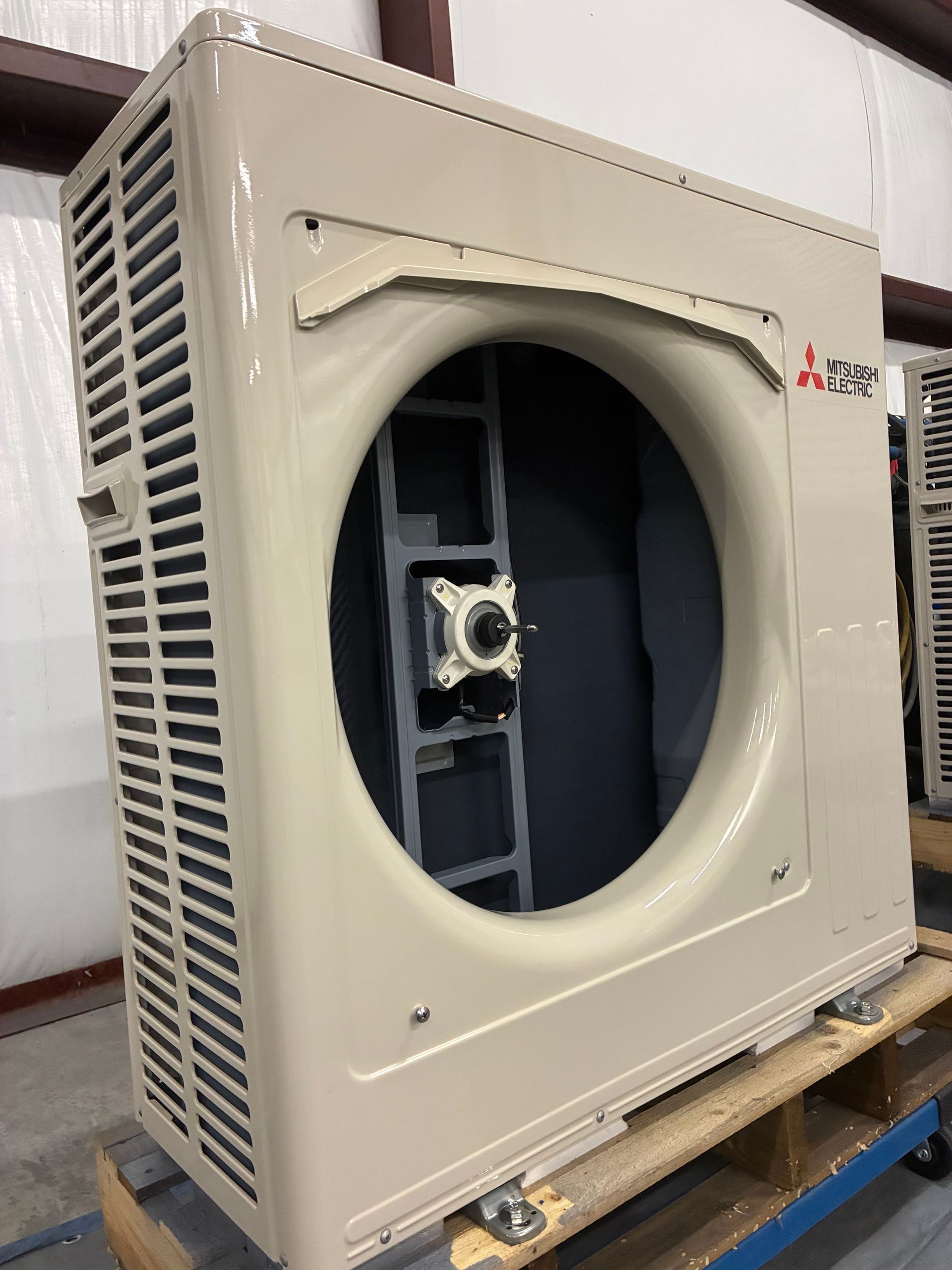A blue air conditioner condenser coil and internal copper piping mounted on a wooden pallet.