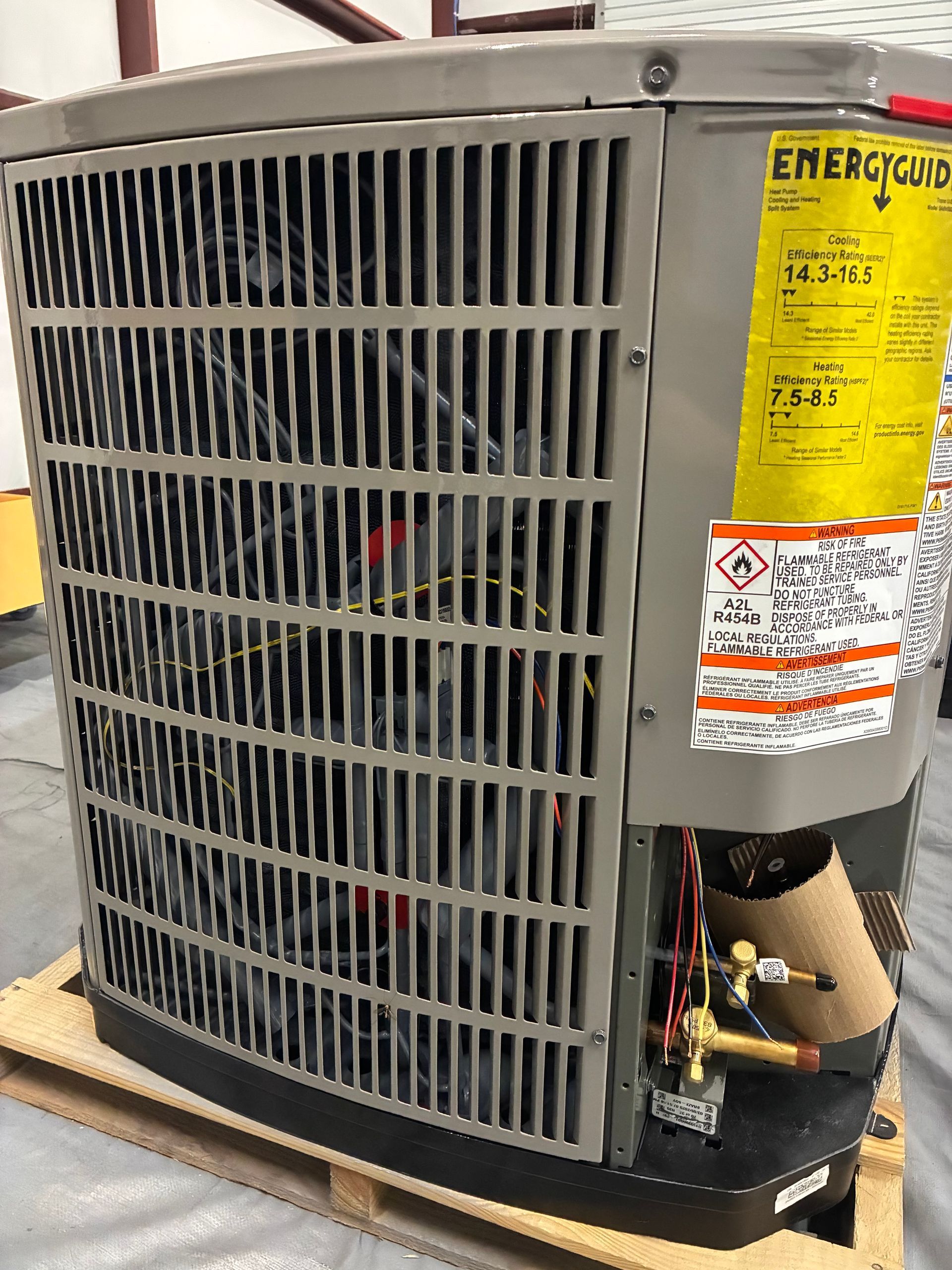 An open HVAC unit cabinet showing two grey vertical compressors connected by pipes and wiring against a metal frame.
